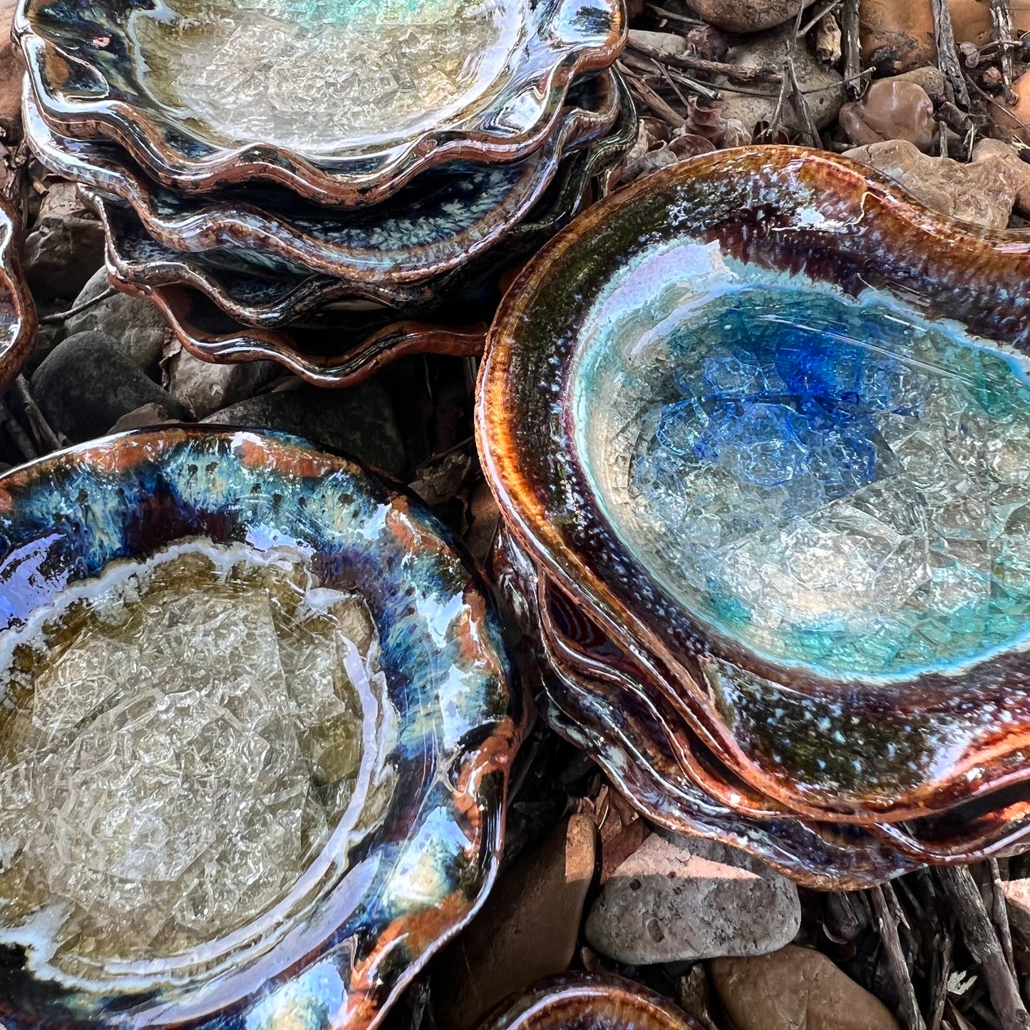 blues and browns crackled glass little dish stacked on a bed of leaves and rocks