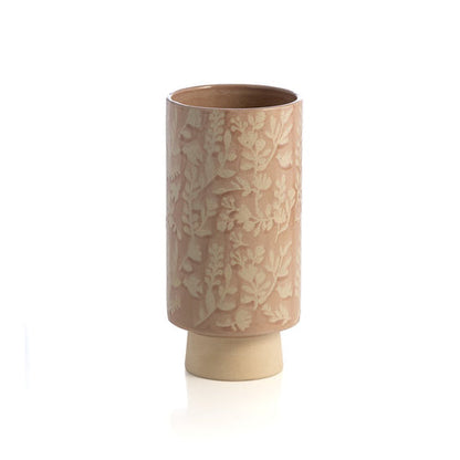 cylindrical vase with blush pink glaze and floral design on white background.