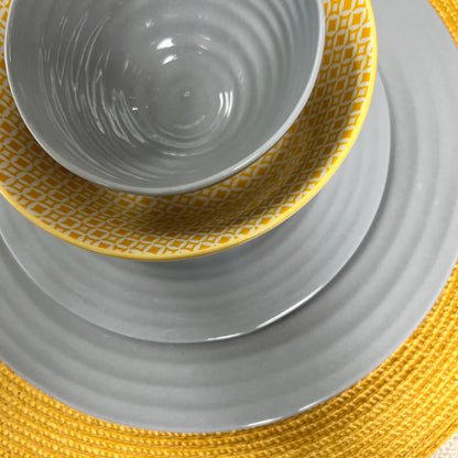 top view of table setting with yellow place mat, grey plates, yellow bowl, and small grey bowl.