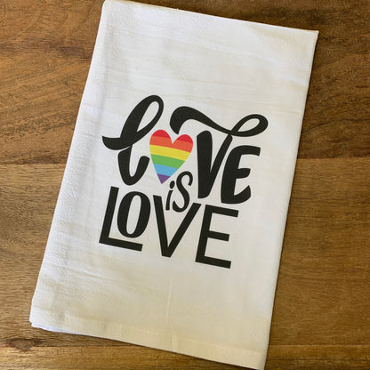 love is love flour sack towel on a wooden surface
