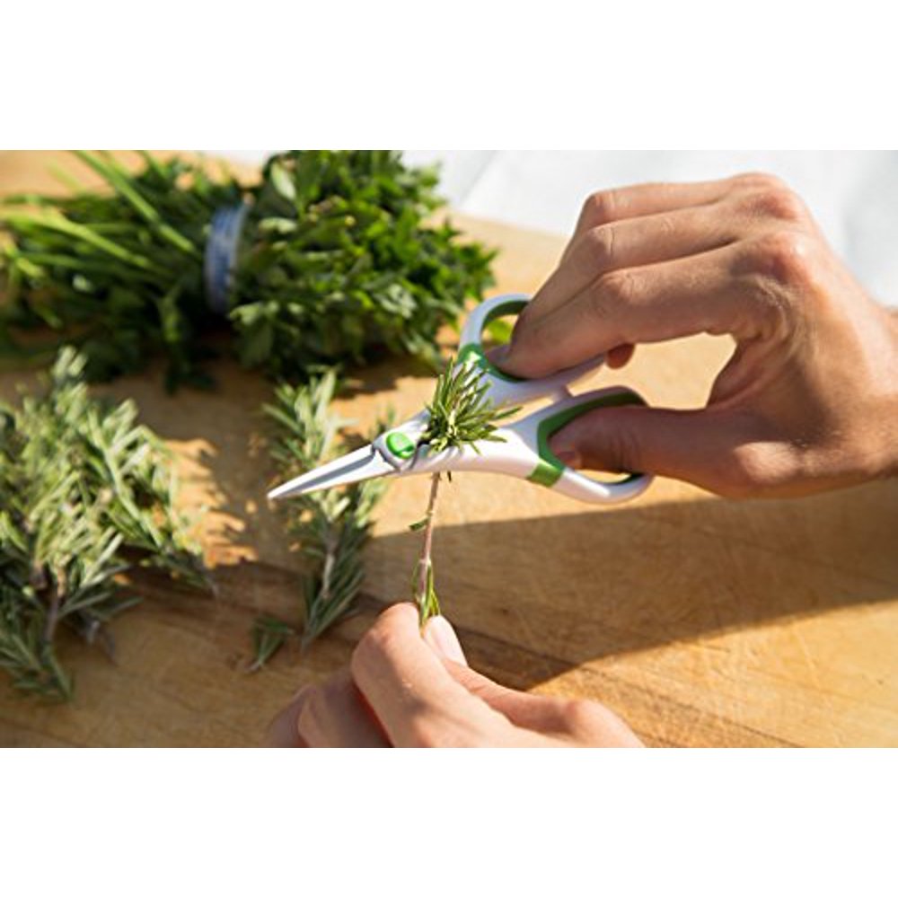 hands stripping herbs over a wooden cutting board