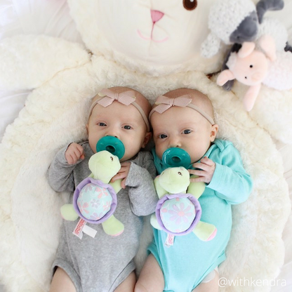 two infant girls laying on the lamb baby mat