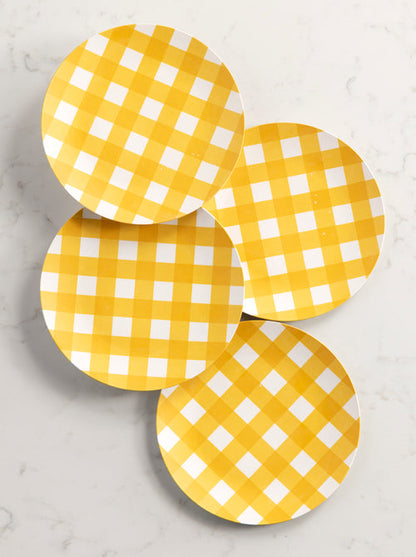 4 salad plates with yellow and white check pattern arranged on a marble background.