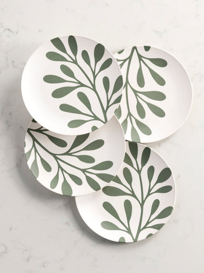 4 dinner plates with a leaf pattern arranged on a marble background.