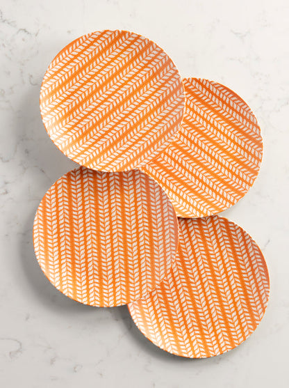 4 orange and leaf pattern dinner plates arranged on a marble background.