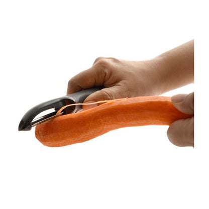 hands holding peeler and peeling a carrot.