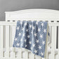 blue chenille blanket with white stars hanging over crib railing.
