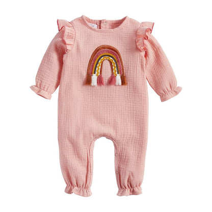 pink outfit with applique rainbow with tassels on the front, elastic at the ankles and wrists, and ruffles at the shoulders.