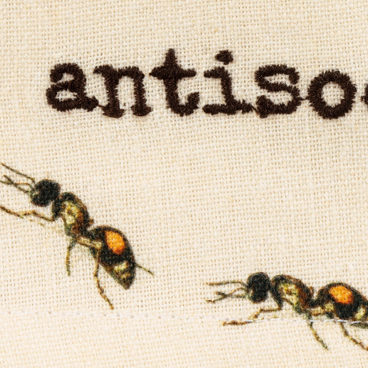close-up of embroidered "antisocial" and ant graphic.