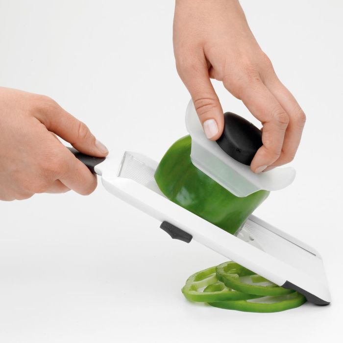 hand holding slicer slicing green bell pepper.