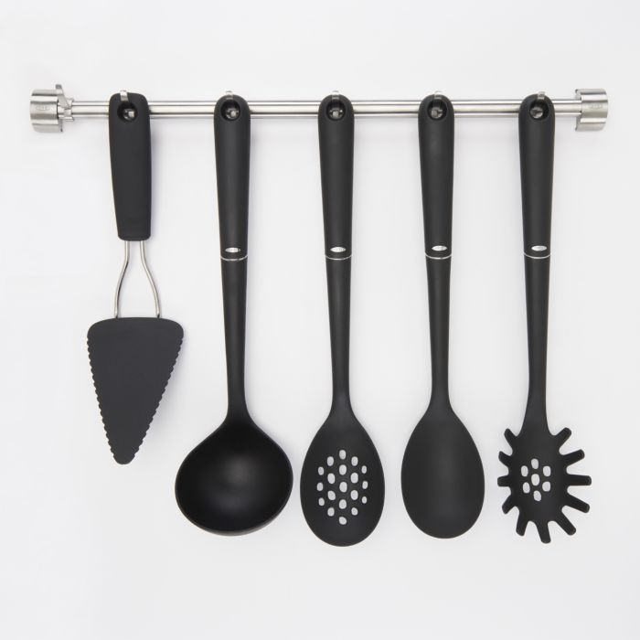 variety of black utensils hanging on utensil bar.