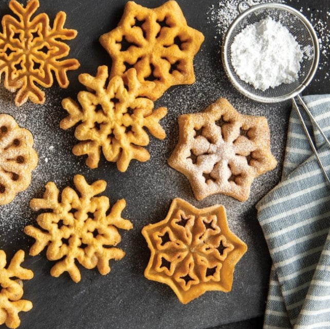 multiple swedish rosettes display with a dusting of powdered sugar and a towel on a gray background