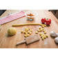 the cousin lianas gnocchi board displayed on a wooden surface surrounded by gnocchi dough tomatoes a towel and heads of garlic