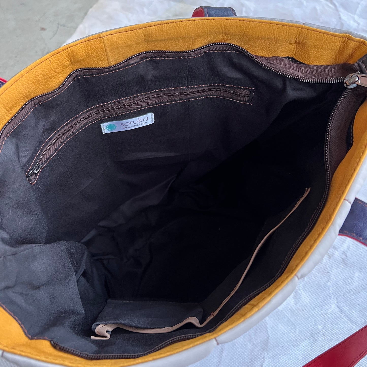 interior view of tote showing black lining and slip and zippered pockets.