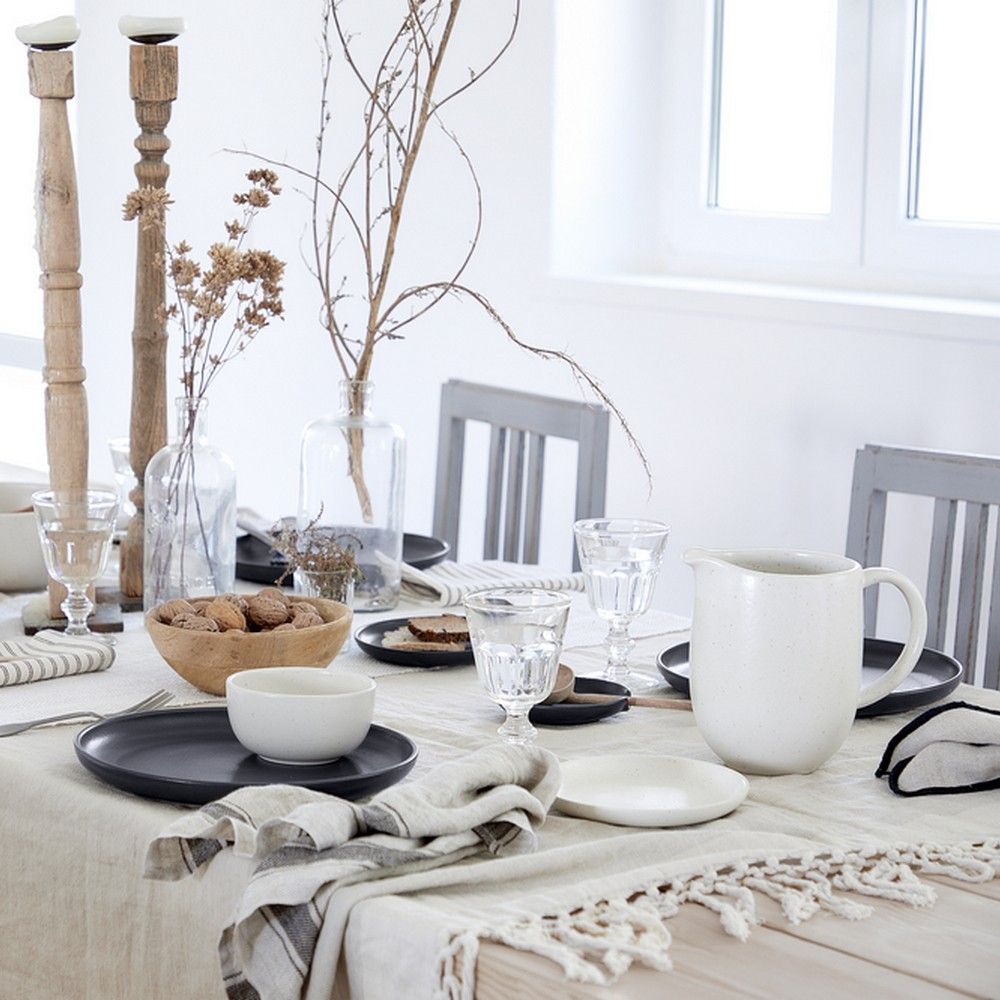 a table setting with pacifica pitcher, dinner plates, drinking glasses, napkins, serving bowls, candle sticks, decor picks in vases on a tablecloth 