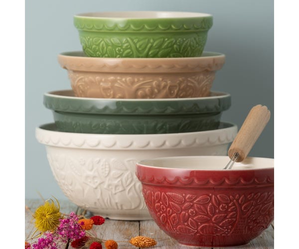 stack of colorful bowls with a red bowl in front on a wooden table.