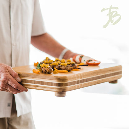 hands carrying board arranged with appetizers.