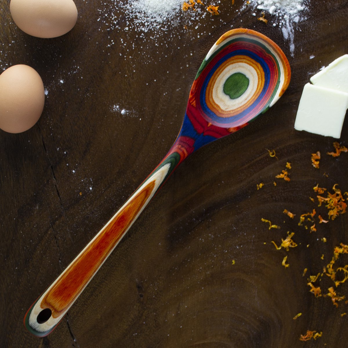 colorful spatula, eggs, and flour on wooden background.