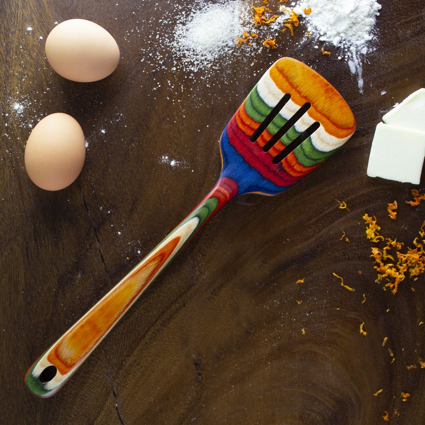 spatula, eggs, and flour on wooden countertop.