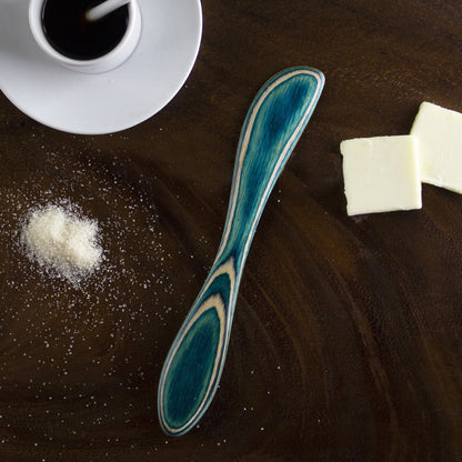 spreader on wooden countertop with butter and syrup.