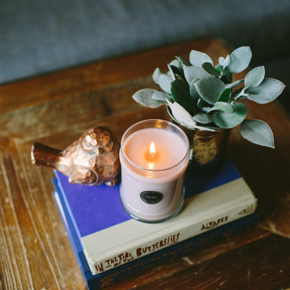 sweet grace candle on a stack of books sitting on a table with decor