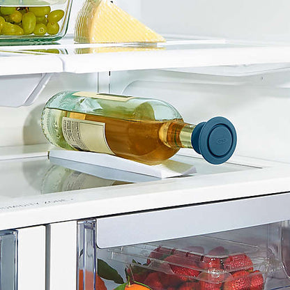 wine bottle in refrigerator laying on its side with blue silicone stopper in it.