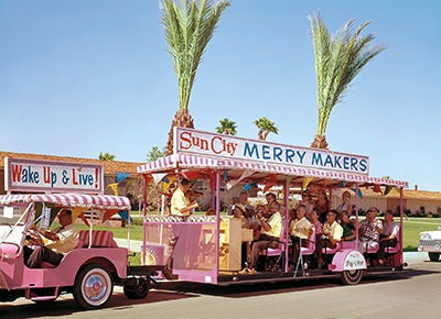 front of card is a photograph of a pink golf cart pulling a covered pink trailer full of people