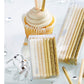 packages of white and golden candles on a table with cupcake and confetti.