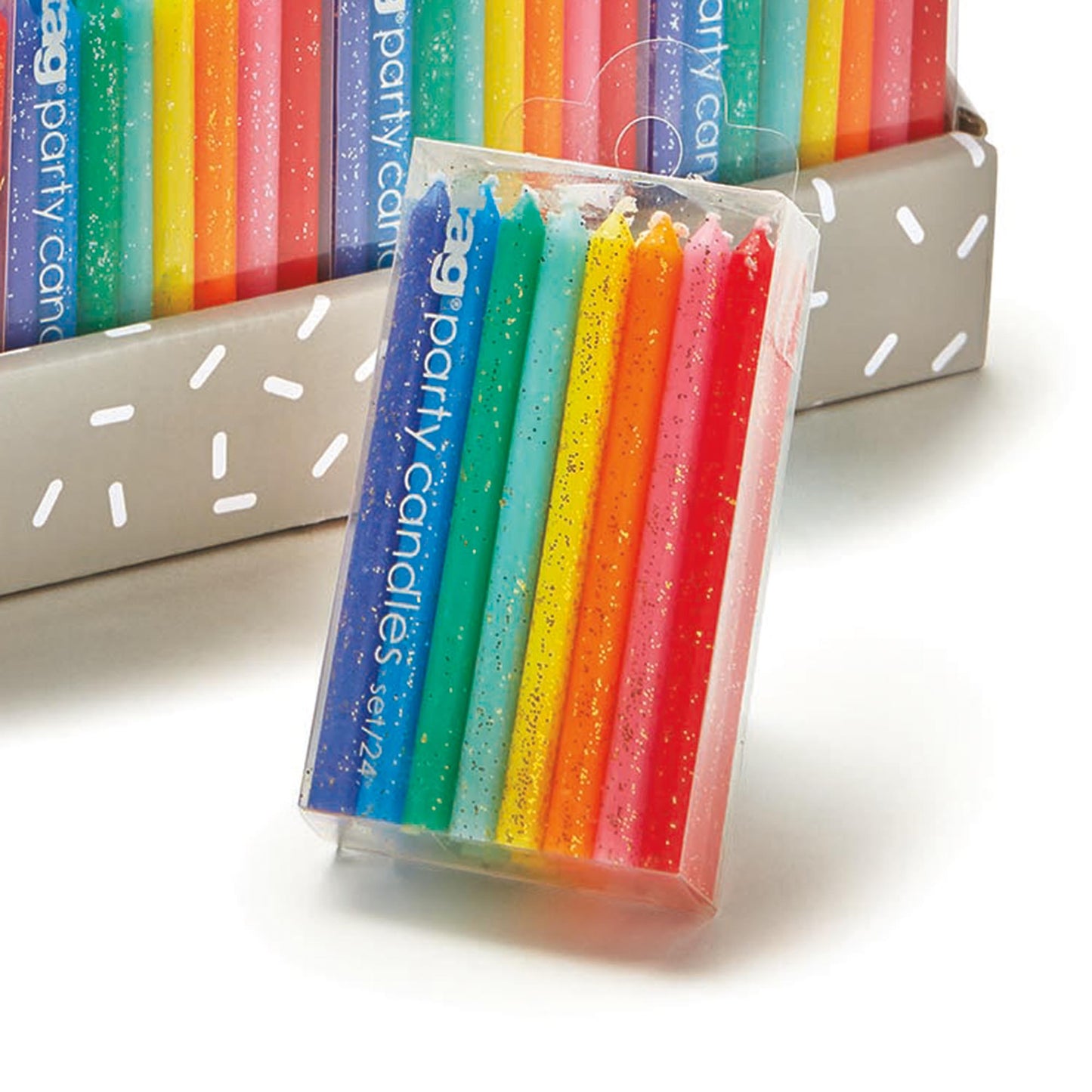 rainbow colored and glittered candles on packaging on white background.