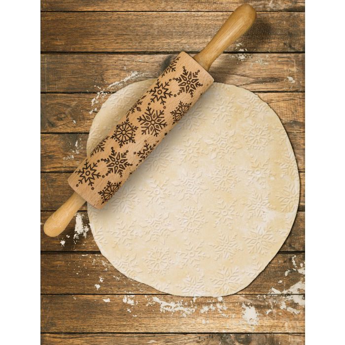 the snowflake design rolling pin displayed on rolled out pastry on a wooden surface