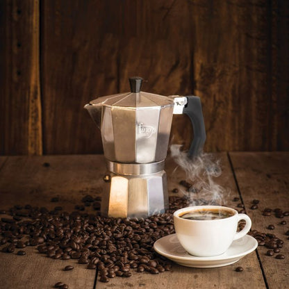 the stovetop espresso maker displayed on a rustic wood surface surrounded by coffee beans and a cup of coffee