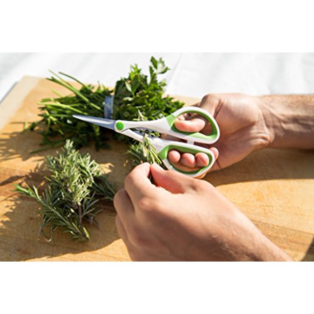 hands trimming herbs over a wooden cutting board