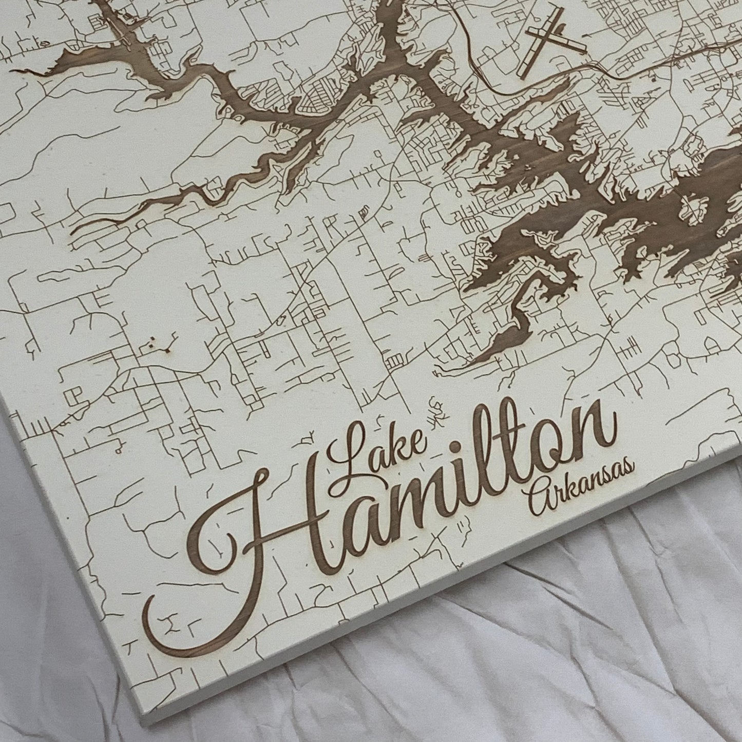 close up view of the burnt wood map of Lake Hamilton in ivory on a white background