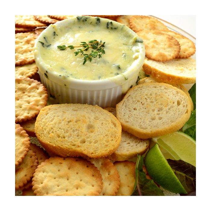 ramekin filled with cheese dip surrounded by bread and crackers.