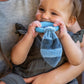 a woman holding a little girl while she chews on the leika little raccoon teether