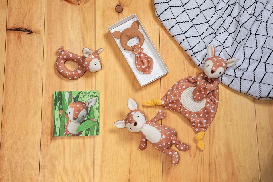 fawn stuffed animal, lovey, book, and teether arranged on wood flooring.