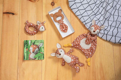 fawn stuffed animal, lovey, book, and teether arranged on wood flooring.