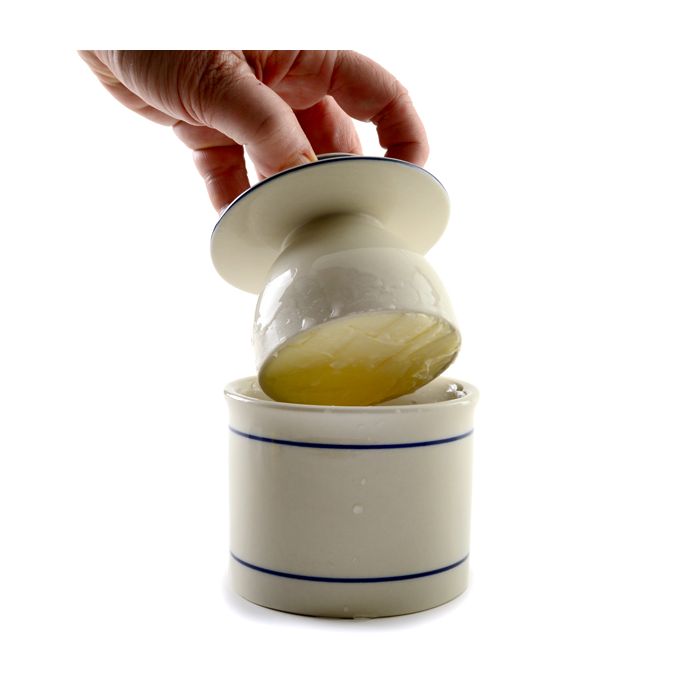 hand putting filled butter keeper onto base.