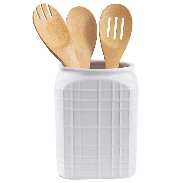 square white utensil crock with line pattern and wooden utensils in it.