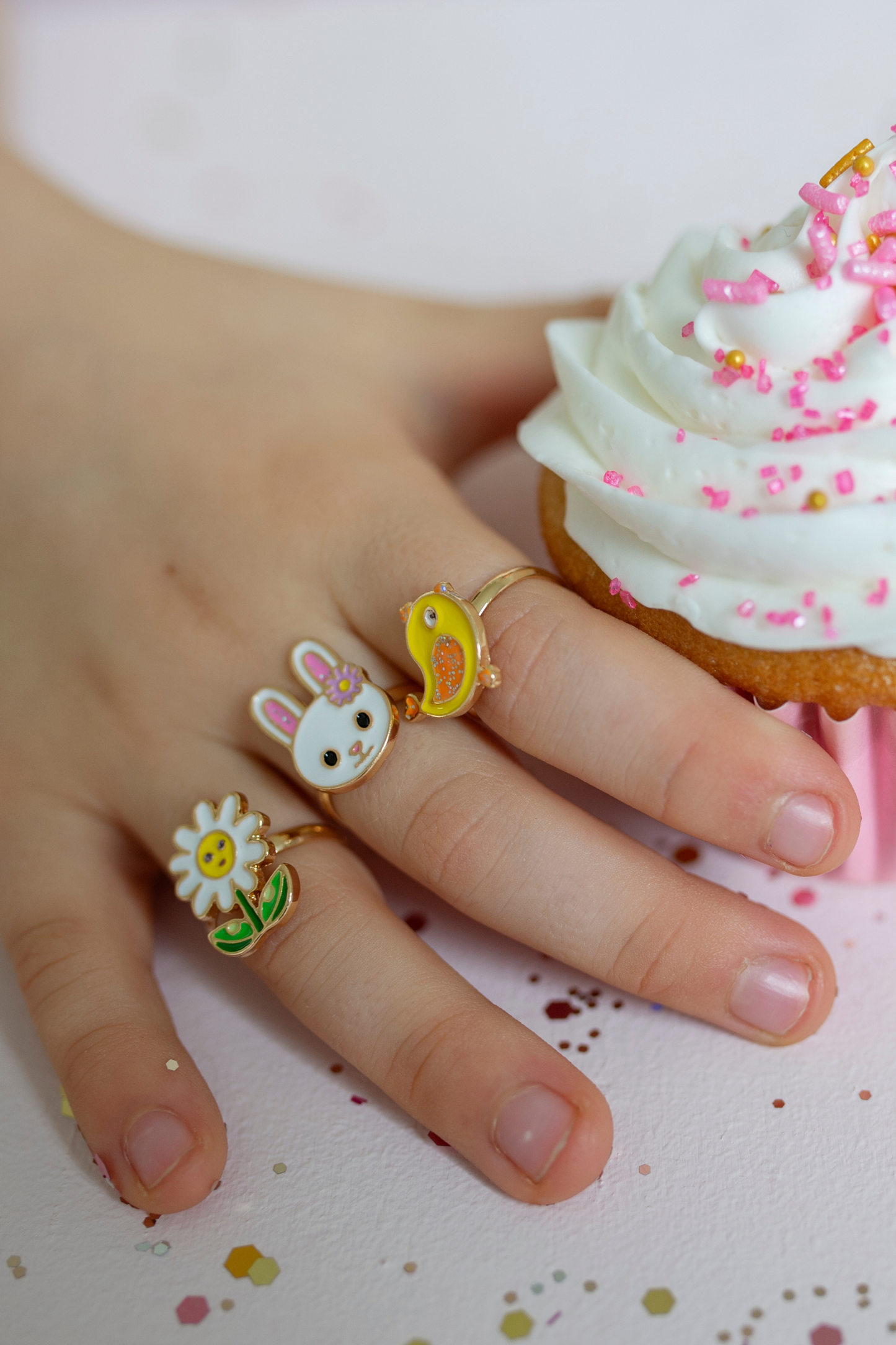 the three spring ring set on a little girls hand while holding a cupcake