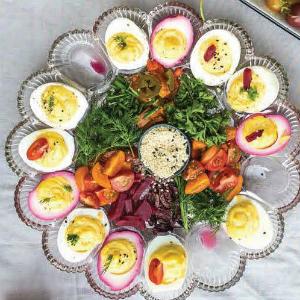 egg tray filled with deviled eggs around the rim and veggies in the center.