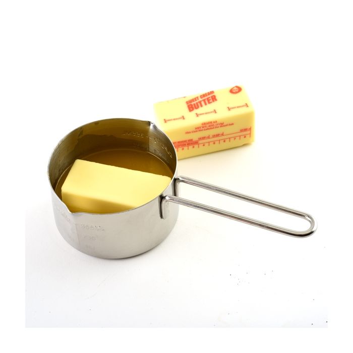 Stainless Steel Measuring Cup with half a stick of butter in.