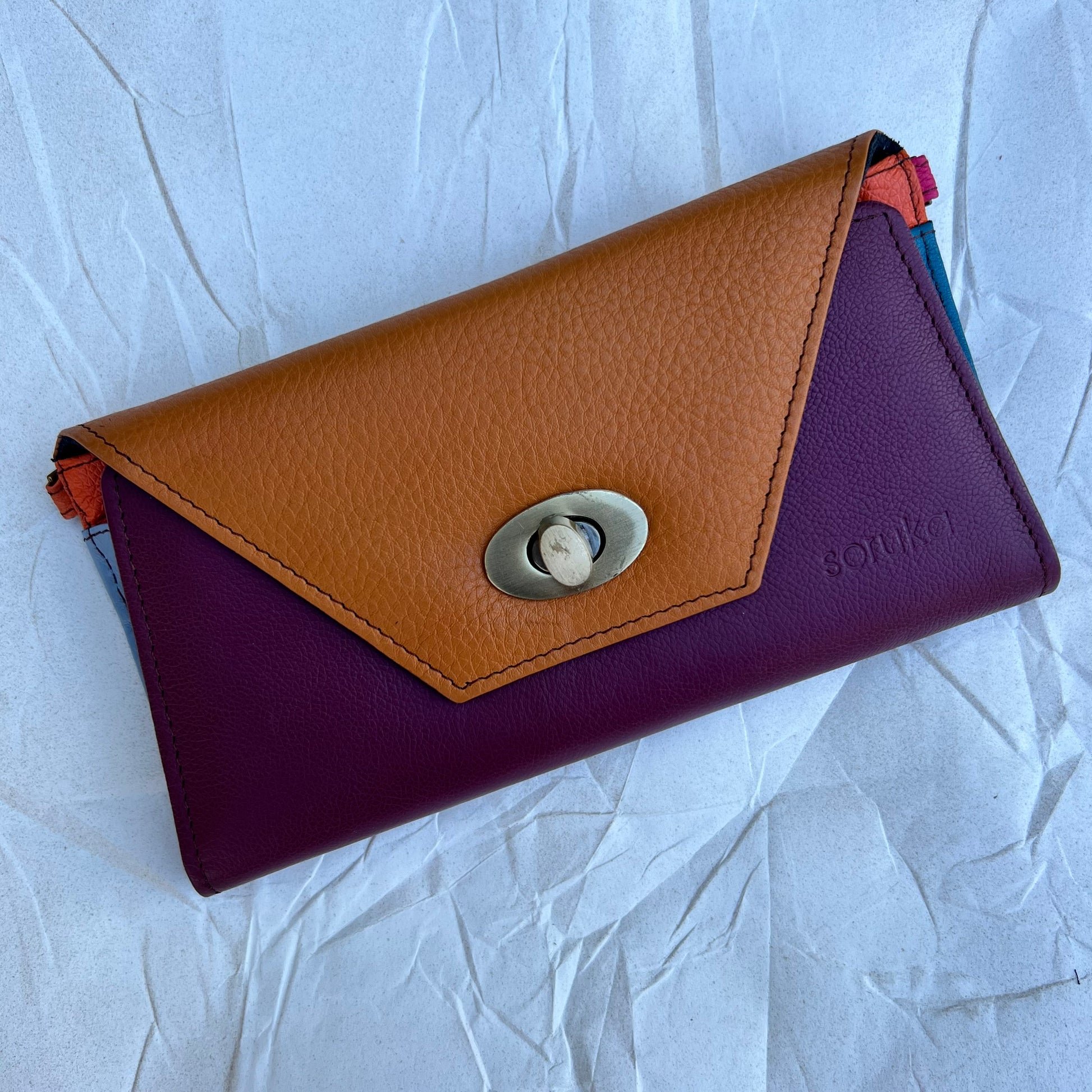rectangle maroon and mango secret clutch against a light blue background