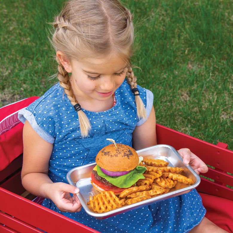 child sitting in wagon with tray of burger and fries.