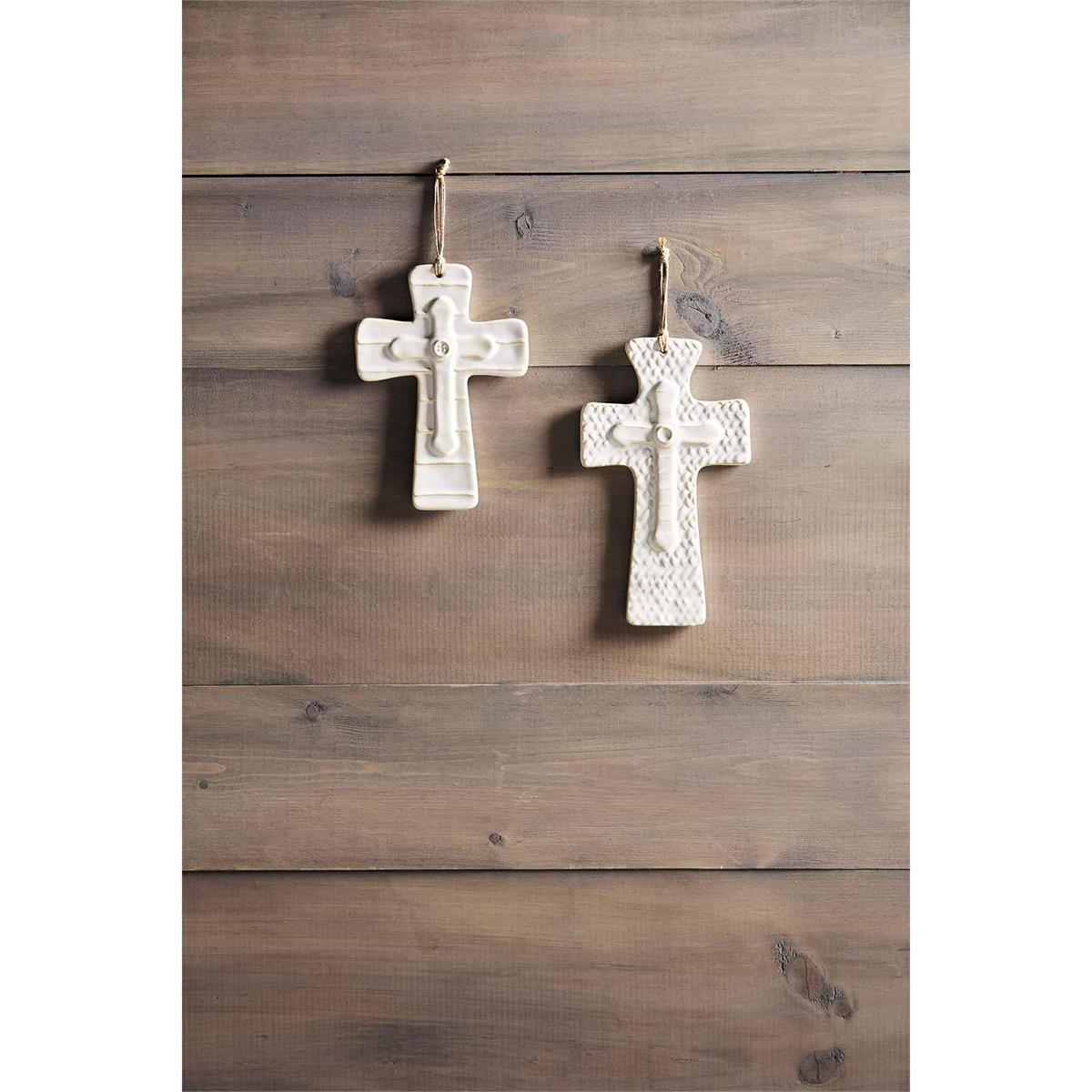 layered stoneware crosses hanging on a dark wood slat wall