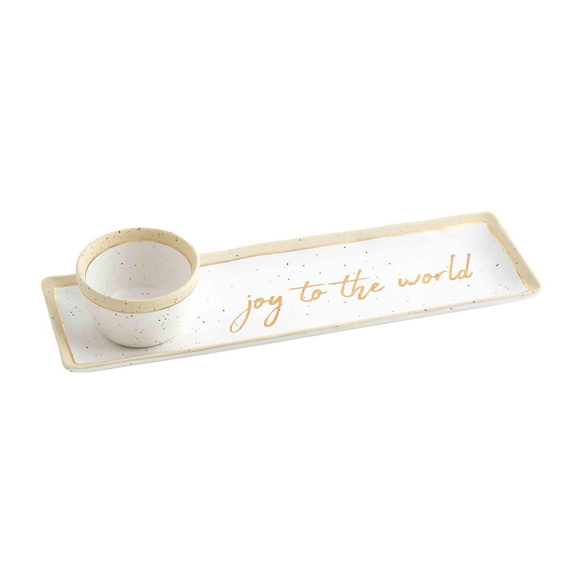 white ceramic tray with exposed rim and gold trim and "joy to the world" painted in gold in the middle. matching small dip bowl is set on one end of tray.