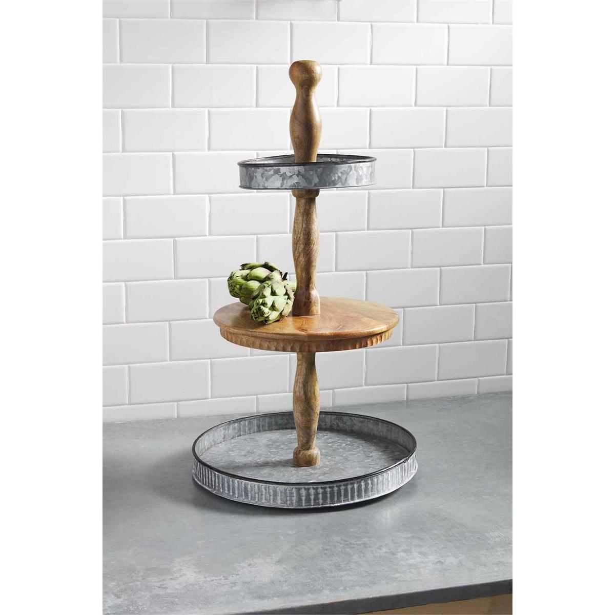 tin and wood tiered server displayed with two artichokes on a dark gray countertop