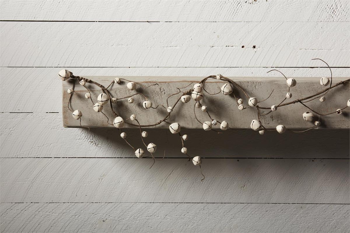 white jingle bells on brown wire draped along a board.