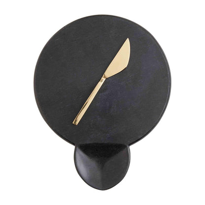 black round cheese board and gold spreader displayed on a white background