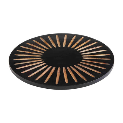 black lazy susan with carved sunburst pattern against a white background
